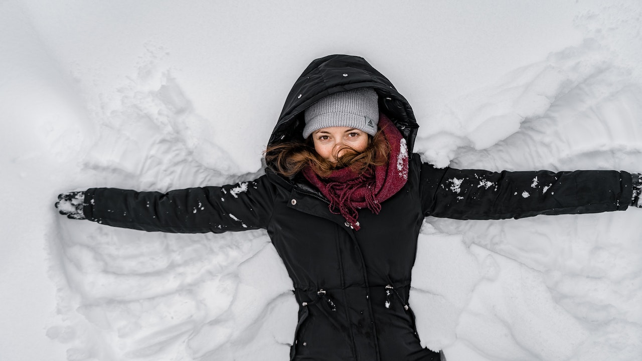 kobieta w kurtce i czapce na śniegu
